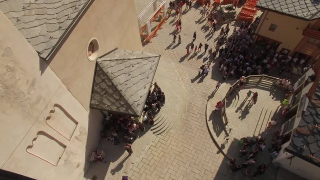 4k Aerial view of old Italian town square with crowd full of people waiting for newlyweds come out from church. Drone top shot of Parish of Saints Pantaleon and Valentine in center of Courmayeur Italy