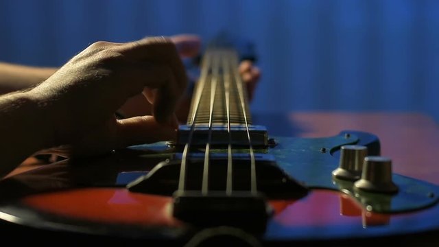 Plays bass guitar closeup
