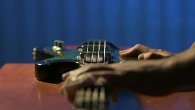 Luthier gently rubs strings vintage bass guitar