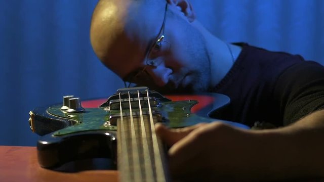 Luthier examines case of vintage bass guitar in repair shop