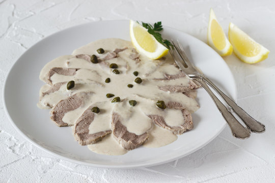 Vitello tonnato is a traditional italian dish on a white concrete background.