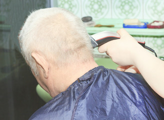 A man gets a haircut in the barber shop. Hairdresser cutting the client's hair in the salon. Elderly hair close-up.