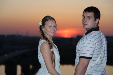 Happy young couple looking back over the beautiful sunset background 