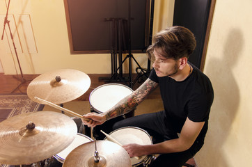Handsome young man playing drums in studio 