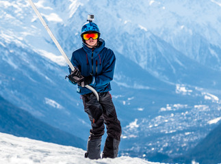 Fototapeta na wymiar Snowboarder in rainbow goggles and blue helmet using a ski lift - a drag or poma lift with the Chamonix valley in the background