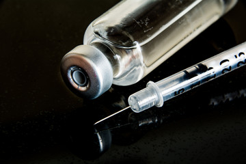 I vial and syringe against a black background.