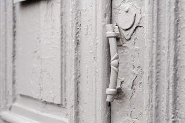 Close-up keyholes with curtains and a handle on the gray many times painted cracked double-barreled wooden vintage door of the last century with a post slit.
