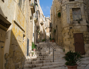 Fototapeta na wymiar Empty stairway between traditional houses in the city of Vittoriosa, Three Cities, Malta