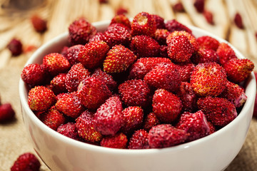 red strawberries in bowl on a wooden background