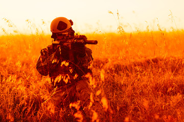 portrait of young soldier face with camouflage against a sunset background