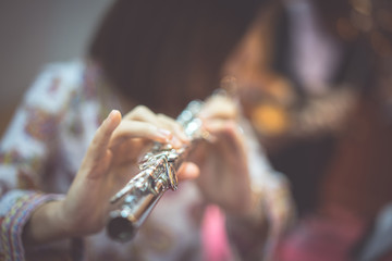 A woman is playing  flute.