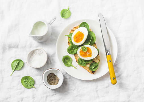 Delicious healthy breakfast - grilled bread sandwich with spinach and boiled eggs on white background, top view
