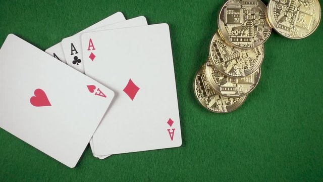 Slow mo gold coins fall on four aces on a green cloth top view