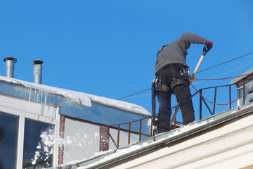 Naklejka premium Work cleans the roof of the house from snow