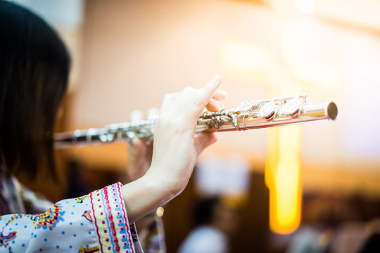 A woman is playing  flute.