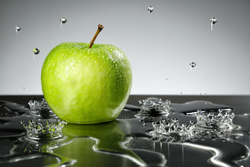 Green apple with water drops on grey background