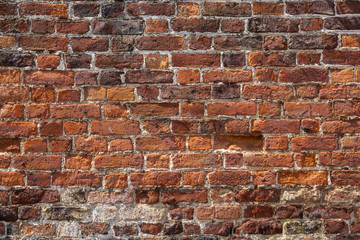 An old weathered, damaged, badly repaired red brick wall full frame