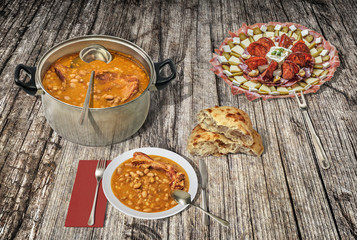 Appetizer Savory Dish And Beans Baked With Smoked Pork Ribs Served With Domestic Leavened Flatbread On Old Weathered Cracked Rustic Wooden Garden Table