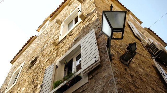 Nice old stone house with many white windows and lanter. View from below and corner. Mediterranean style of buildings. Outdoor