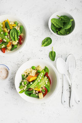 Pearl couscous with fresh vegetables bowl. Young green peas pod, corn, baby carrots, spinach, beans. On a light background. Food concept.