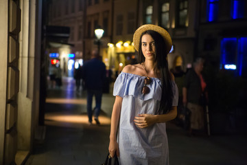 Young woman in hat walking at night city centre