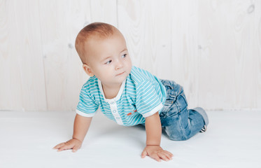 The kid resting on his hands looks mysteriously to the side on a light background