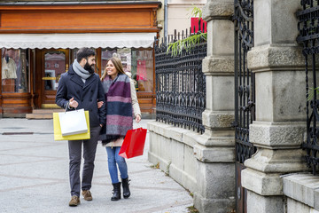 Happy young couple with shopping bags on the street looking happy and satisfied