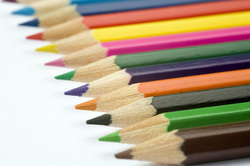 Childrens colouring pencils on a plain white textured paper background