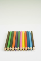 Childrens colouring pencils on a plain white textured paper background