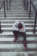 The man in despair, depressed bent his head, sitting on the steps.