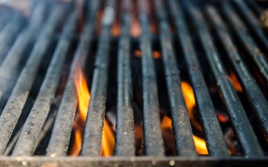 Grill bbq close up and bright hot flames, outside summer cookout, empty barbecue burning wood with smoke, blurred fire and charcoal briquettes