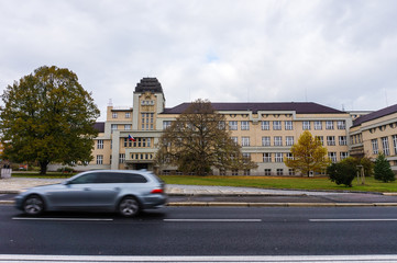 Fototapeta premium Kutna Hora, street with moving car in new town with school, Czech Republic