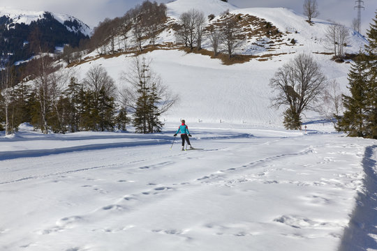 Winterpanorama im Salzburger Land in den Kitzbühler Alpen (Mooralm) mit Langlaufloipe und Langläuferin