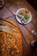 assorted salads in mediterranean restaurant  with focaccia bread in background on wooden table
