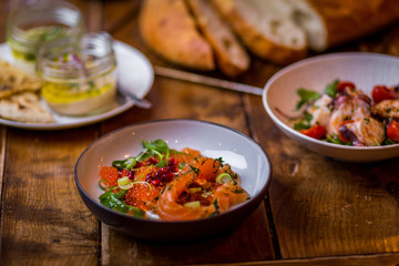 assorted salads in mediterranean restaurant  with focaccia bread in background on wooden table