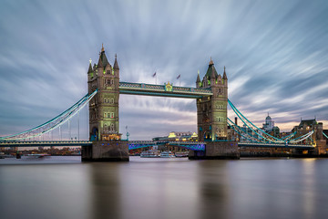 Die beleuchtete Tower Bridge am Abend in London mit bewölktem Himmel