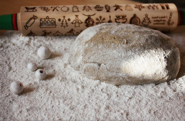 Dough for festive baking homemade ginger biscuits. Skalka for dough for the formation of cookies with patterns of the New Year theme. In the background a wooden rolling pin for baking cookies with pat