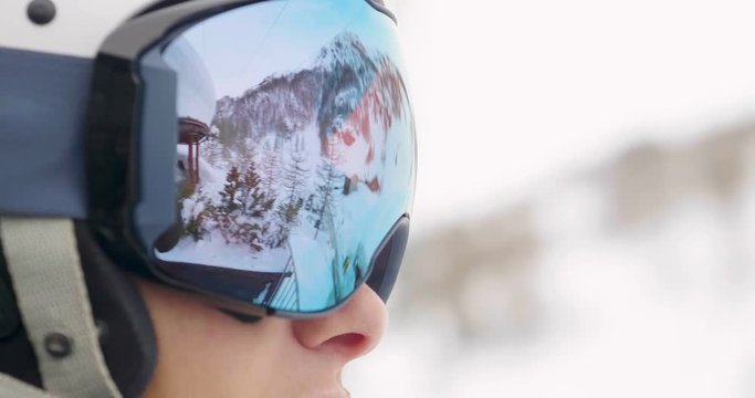 Close-up of a smiling skier's face on a vacation in the mountains, peering over the ski slopes. Concept of: holidays, sport, passion, skiing.