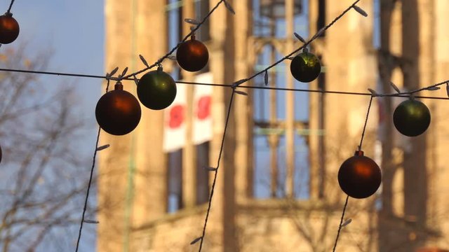 Zoom onto Christmas decoration baubles hanging above in the street outdoors