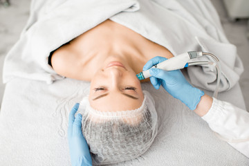 Young woman during the facial treatment procedure in the cosmetology office