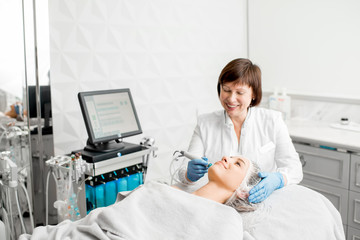 Senior woman cosmetologist making facial procedure to a young client in a luxury medical resort office