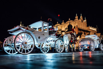 Obraz premium The old square of the night krakow with horse-drawn carriages