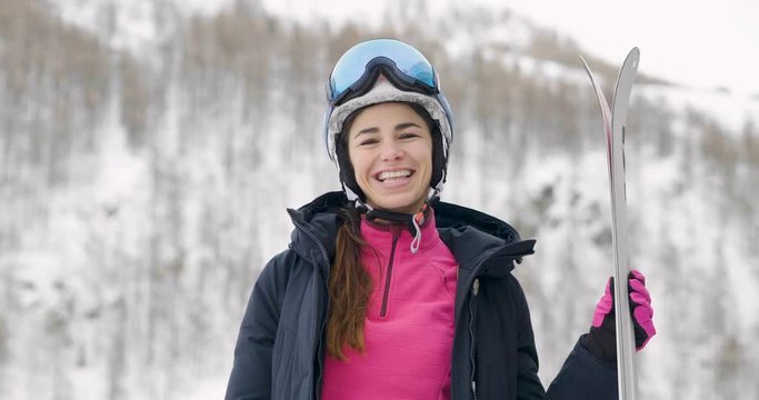Portrait of a smiling skier on vacation in the mountains, behind her you can see the snow-covered mountain. Concept of: holidays, sport, passion, mountain.