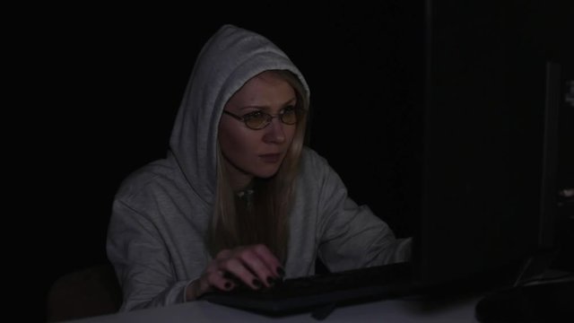 A woman hacker at the computer at night.