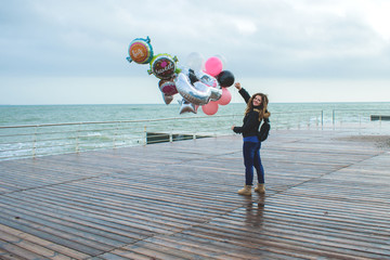 portrait of a girl with balloons that walks along the embankment.