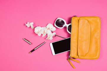 Woman's accessories lying flat on pink paper table background. Pastel colors with copy space around products . Image taken from above, top view. Minimal style with room for text