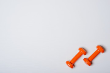 Two dumbbells of orange are lying on a white background with a tree texture