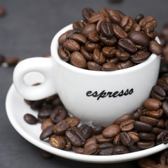 Still life of roast coffee beans and espresso cups on a tiled kitchen work surface