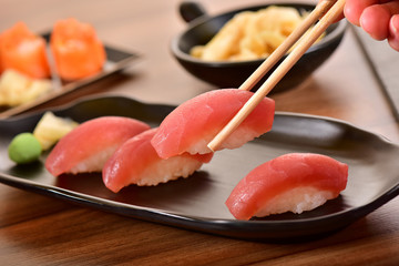 Chopsticks holding a Tuna nigiri sushi