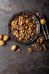 Walnut kernels and whole walnuts on rustic old wooden table